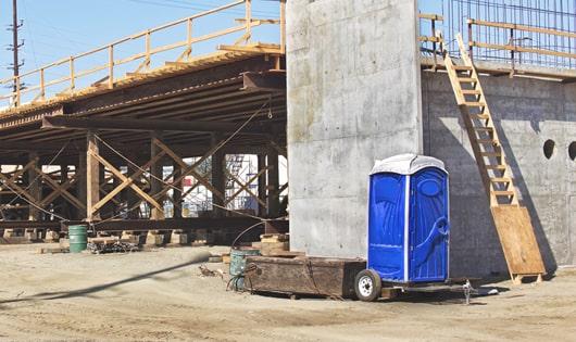 a row of blue portable restrooms set up on a job site